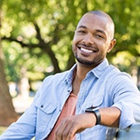 Smiling man with denim jacket sitting on bench