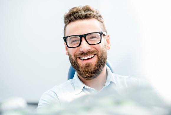 man smiling while sitting in dental chair 