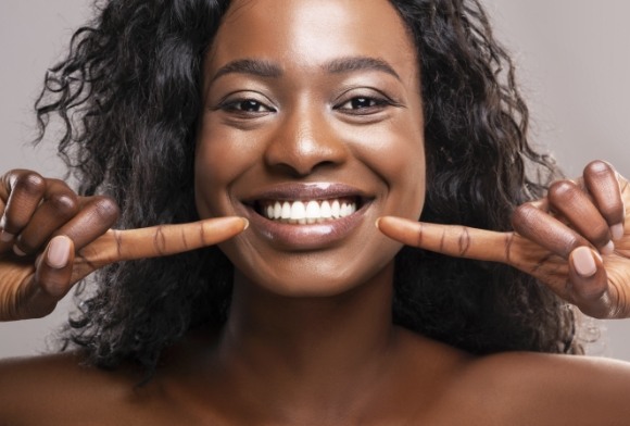 Woman pointing to smile after treatment for cracked tooth syndrome