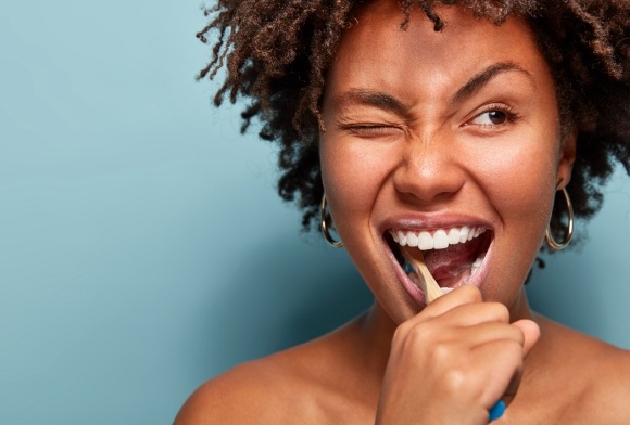 Woman brushing teeth to care for dental crowns