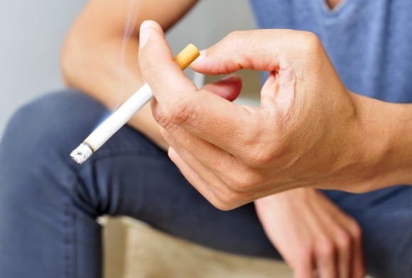 Person smoking a cigarette which can contribute to dental implant failure