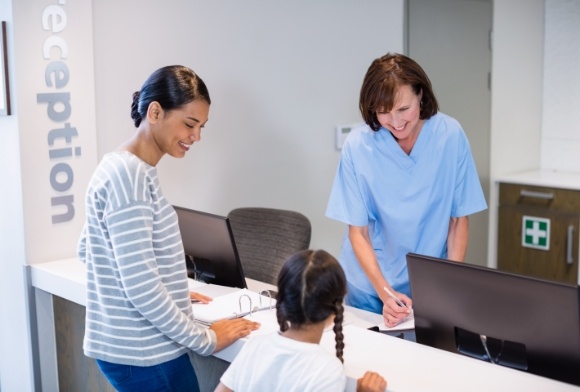 Mother and daughter working with dental team member to maximize dental insurance coverage