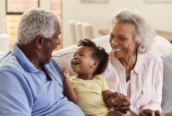 Grandparents smiling at grandchild enjoying the benefits of dentures