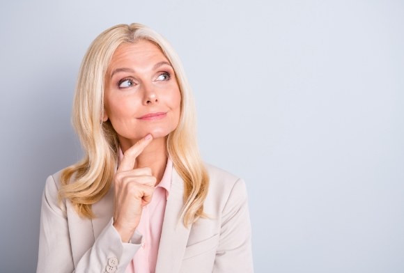 Woman considering the answers to frequently asked questions about dentures