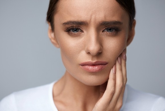 Woman holding jaw before emergency dentistry