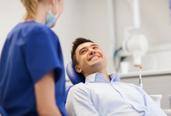 Man smiling at dental team member after emergency dentistry treatment