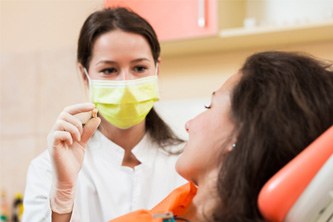 Dentist holding an extracted tooth next to her patient’s mouth