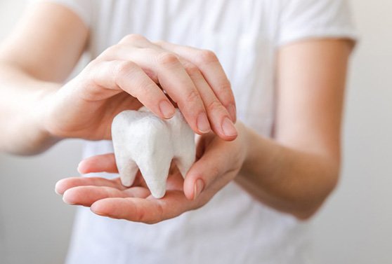 a person holding and covering a tooth