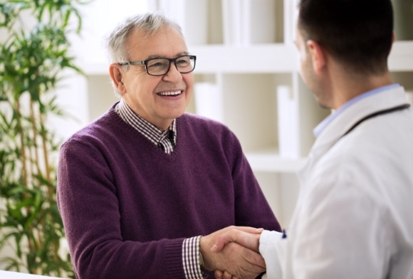 Man shaking hands with dentist after dental implant denture procedure