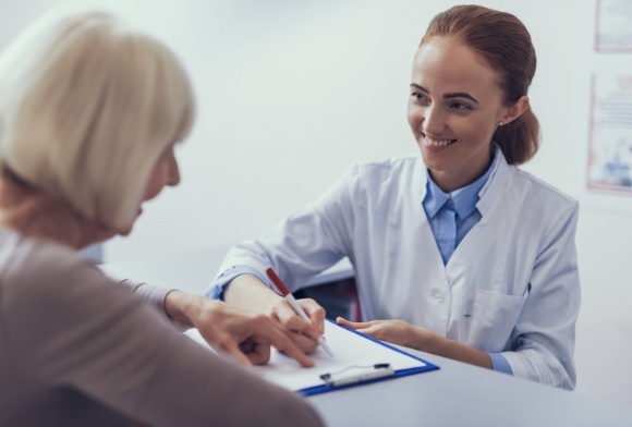 Woman filling out financial forms with dental team member