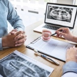 Dentist and patient discussing preliminary treatments and dental implant surgery