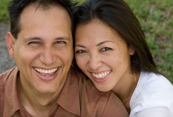 Man and woman smiling together enjoying the benefits of dental implants