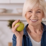 Woman eating an apple after dental implant tooth replacement