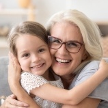 Older woman hugging her grandchild enjoying the health benefits of dental implant tooth replacement