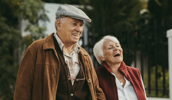 Older man and woman with healthy smiles after replacing missing teeth