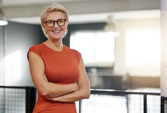 Woman with glasses smiling with her arms folded