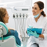 Dentist smiling while talking to patient at routine checkup