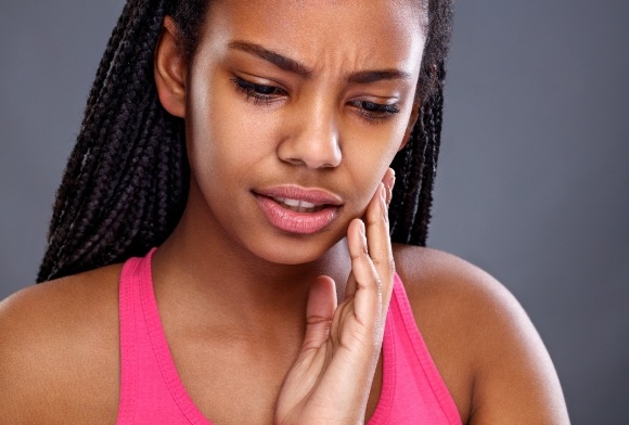 Woman in need of emergency dentistry holding cheek in pain