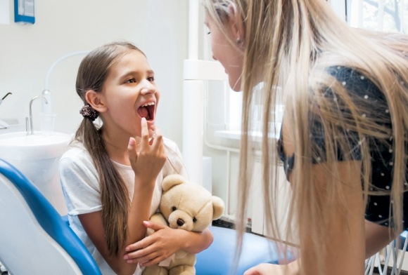 Child pointing to smile during children's dentistry visit