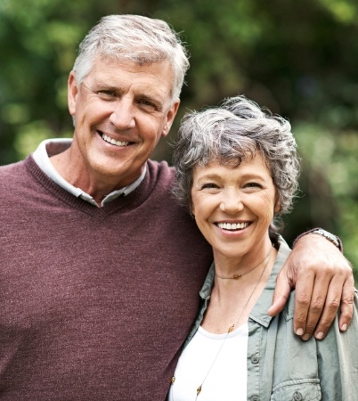 Man and woman smiling after replacing missing teeth