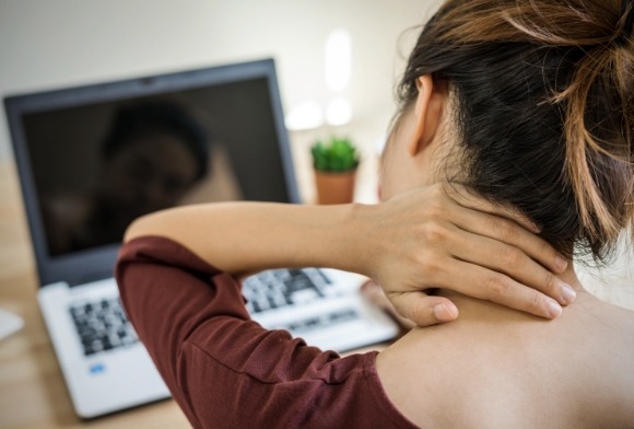 Woman in need of T M J disorder holding neck in pain