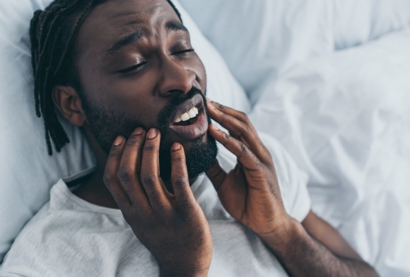 Man with T M J disorder holding jaw in pain