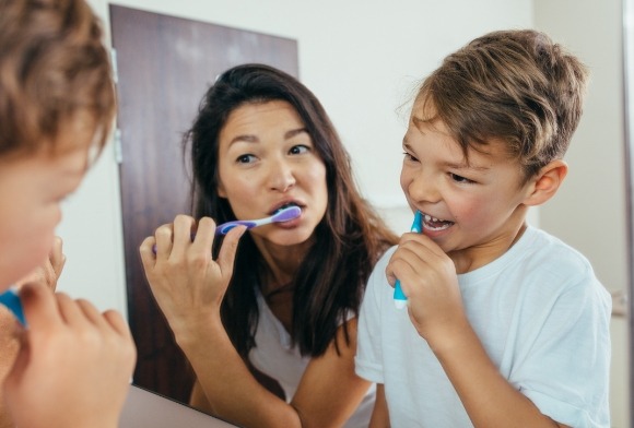 Mother and child brushing teeth to care for smile after tooth colored fillings