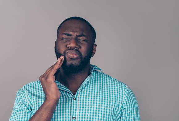 Man in need of toothe extraction holding cheek in pain