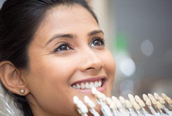 Woman's smile compared with porcelain veneer color chart