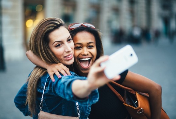 Two women taking picture together after receiving porcelain veneers