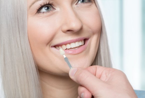 Woman smiling during painless porcelain veneer placement procedure
