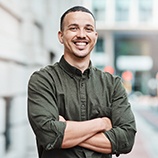 Man in a button-up shirt smiling with arms folded