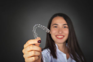 Smiling woman holding Invisalign tray