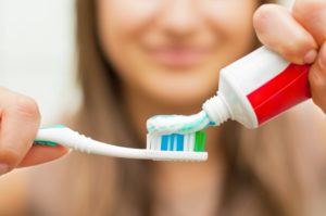 Woman applying toothpaste to toothbrush.