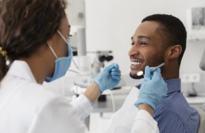 young man smiling at his dentist during a dental cleaning 