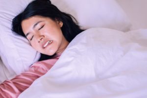 a person grinding and clenching their teeth as they sleep