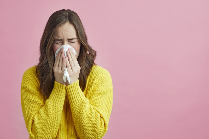 Woman blowing her nose due to her allergies