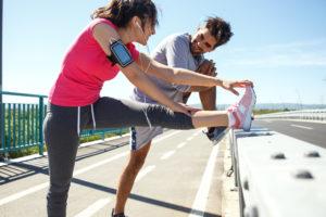 Two runners stretching and smiling on summer day