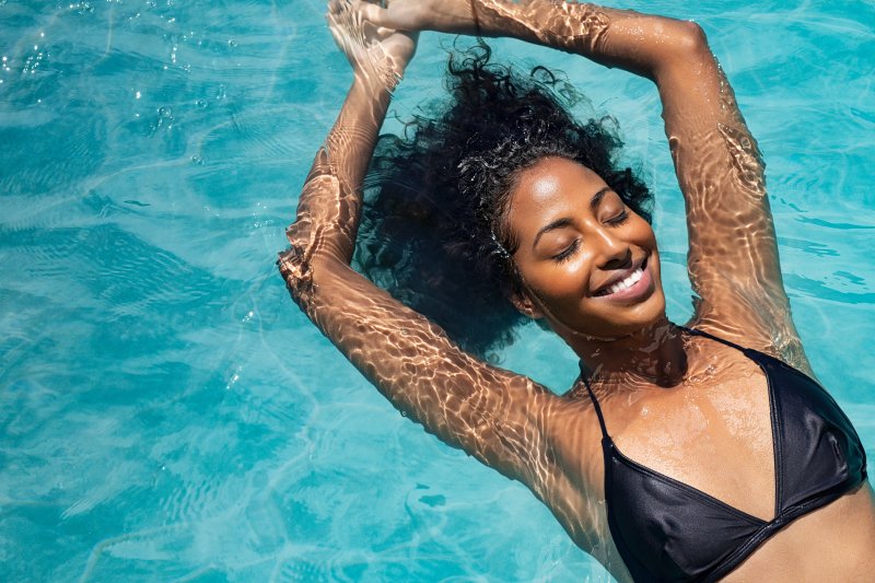 a woman floating face up in a swimming pool and enjoying the cool water