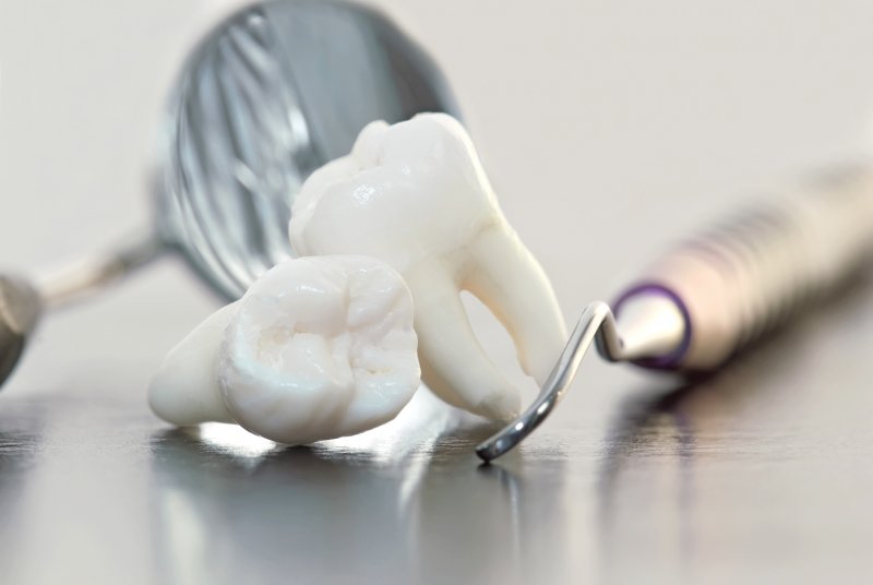 Wisdom teeth laying next to dental tools on a grey countertop