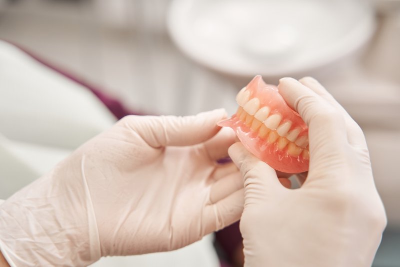 A closeup of dentures held by a dentist