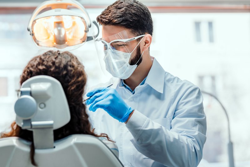 A dentist working in a clinic while a patient sits in a chair