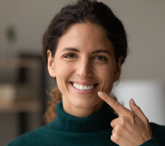 Woman smiling and pointing at teeth