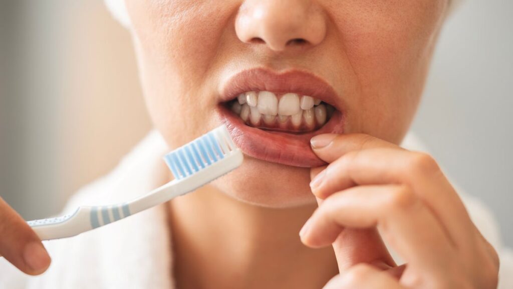 A woman looking at her swollen gums in the mirror